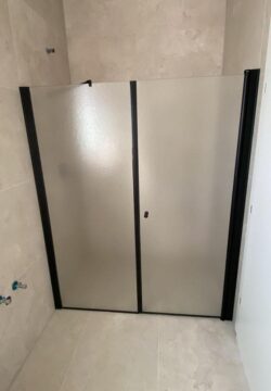 מקלחון חזית לפי מידה קבוע ודלת עם פרופילים שחורים זכוכית גרניט
